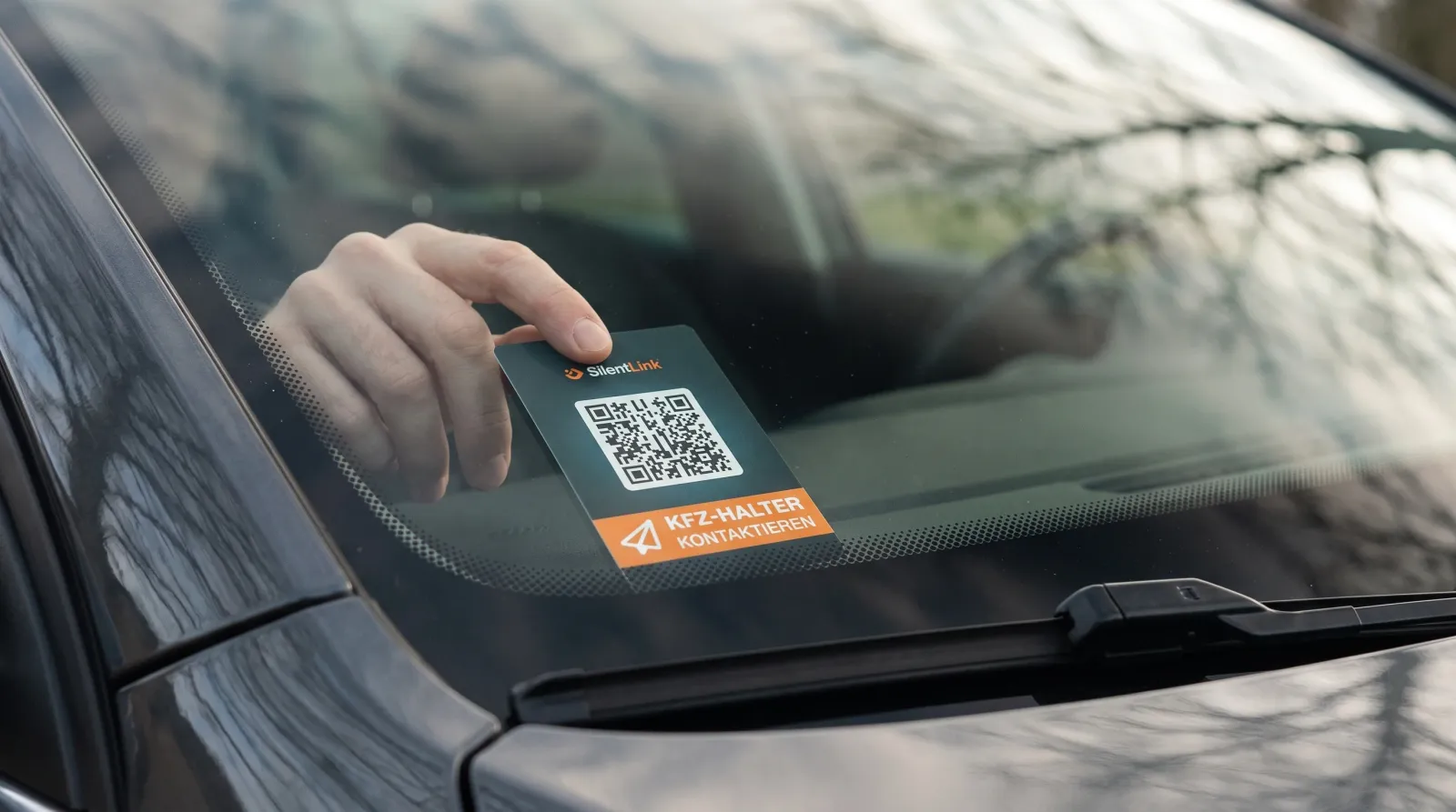 Der QR-Code-Aufkleber DriveID wird von innen an die untere Ecke der Windschutzscheibe gedrückt, von außen durch das Glas gesehen